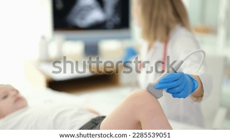 Doctor rheumatologist conducting ultrasound examination of child knee in clinic closeup Royalty-Free Stock Photo #2285539051