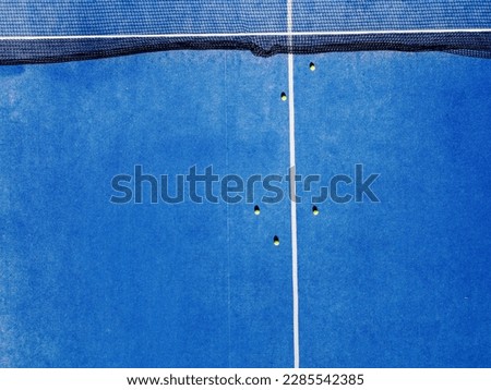 aerial view of a paddle tennis court with several balls on its surface, racket sports background