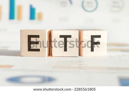 Exchange traded fund. Wooden cubes with ETF text and papers with statistics showing stock market drop. Economic recession and crisis. Investment and trade concept. High quality photo
