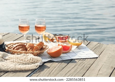 Romantic sunset dinner on the beach. Table honeymoon set for two with luxurious food, glasses of rose wine drinks in a restaurant with sea view. Summer love, romance date on vacation concept.