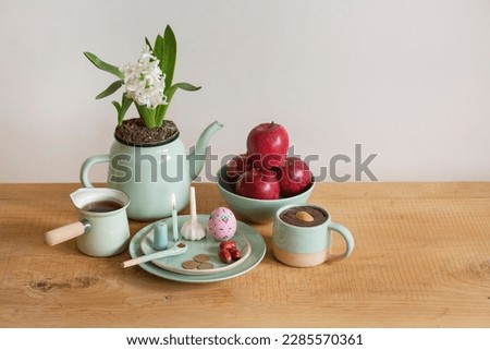 
Nowruz festive table, Persian new year decoration, Iranian Haft sin: apple, sumac powder, garlic, vinegar, coins, burning candles, samanu, senjed. Cultural feast.wooden background.Eid Mubarak.