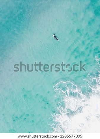 View from above, stunning aerial view of a person surfing on a turquoise ocean. Fuerteventura, Canary Islands, Spain.