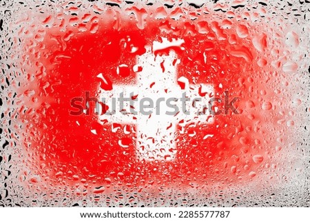 Flag of Switzerland. Swiss flag on the background of water drops. Flag with raindrops. Splashes on glass. Abstract background