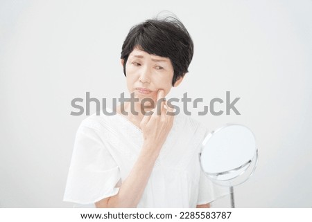 Asian middle aged woman having face skin trouble Royalty-Free Stock Photo #2285583787
