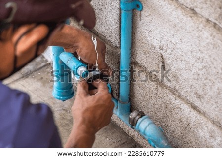 A Mechanic Plumber is Repairing a Leaking Water Pipe Tap Near the Water Meter. Royalty-Free Stock Photo #2285610779