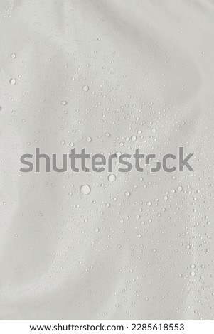 Close-up shot of a waterproof material out of which the protective arm sleeves are made. Water droplets on gray fiber waterproof fabric. Royalty-Free Stock Photo #2285618553