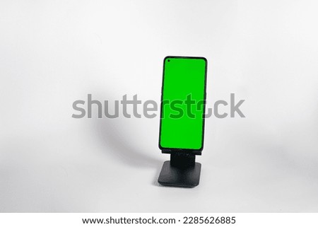 Phone with hole punch placed in stand showing green screen