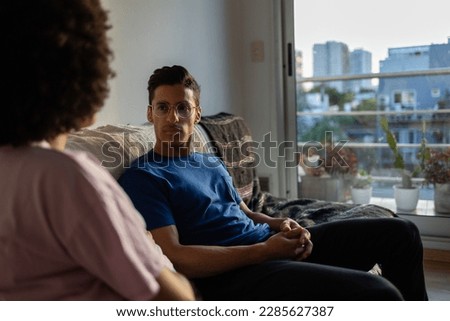 Two latin friends having a serious conversation. they are siting on the sofa in apartment with a window in background Royalty-Free Stock Photo #2285627387