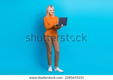Full size photo of intelligent woman orange turtleneck trousers look at laptop on distance conference isolated on blue color background