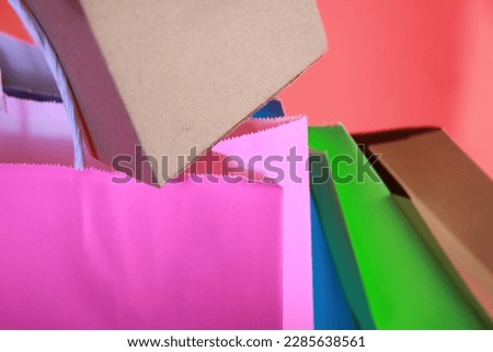 close up of colorful paper shopping bags and cardboard boxes above in orange negative space, perfect for a mockup