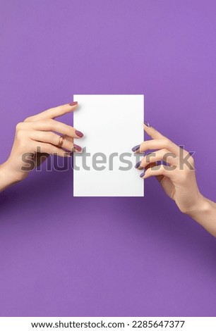 Beautiful womans hand with manicure holding postcard