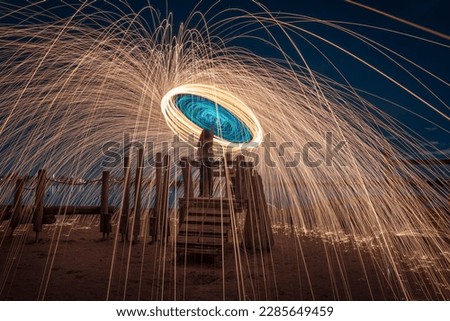 Burning steel wool spinned in urban area. Showers of glowing sparks from spinning steel wool. Man in the fire. 