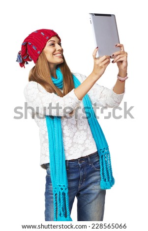 Happy smiling young woman wearing winter clothing having video chat on digital tablet over white background