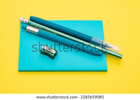 Blue pens, pencil, sharpener, note paper on a yellow background as a concept of work in a modern office