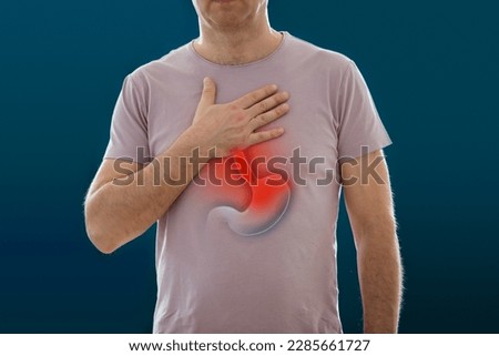 The man standing on a dark background. Picture of a human digestive system and stomach with inflammation. Anatomy of a human with heartburn. Medical concept,  Intestinal diseases