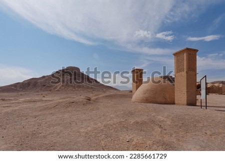 View of a windcatcher and water reservoir with a Tower of Silence in the background in Yazd Province, Iran