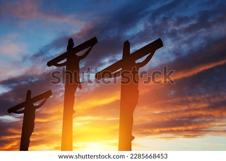 Silhouette of the crucified Jesus Christ on the cross along with other people on background of sunset sky. Concept.