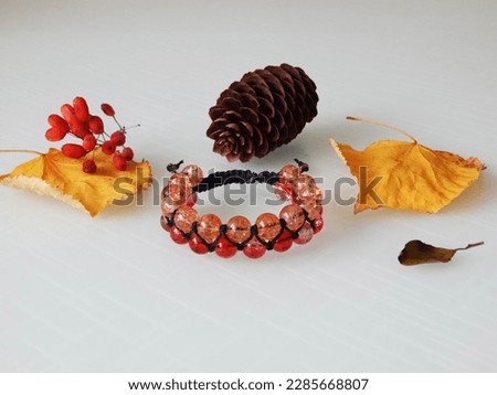 Orange friendship bracelet and leafs. Hippie orange bracelet on a white
