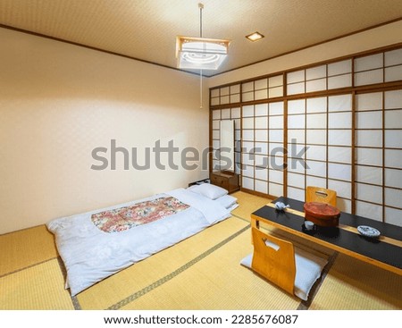 Photograph of a Japanese-style bedroom representing the core of Japanese design, including tatami mats that cover the floor, shoji doors and fusuma walls made of rice paper, and a futon mattress. Royalty-Free Stock Photo #2285676087