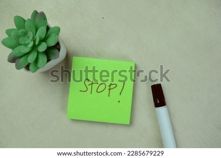 Concept of Stop! write on sticky notes isolated on Wooden Table.