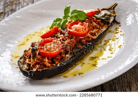 Roasted aubergine stuffed with minced meat and cheese on wooden table  Royalty-Free Stock Photo #2285680771