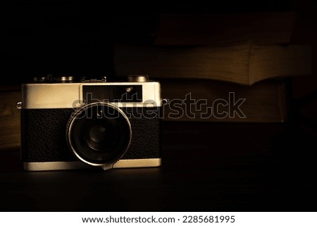 Old vintage camera  on a rustic table against a low light warm  dark background - low light under exposed photography - selective focus