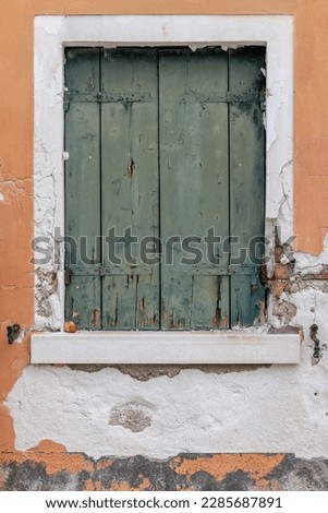 vintage faded old rustic shutters on the island of Burano Italy, traditional Italian colours sunlight faded, famous colourful tourism island near Venice. Background texture