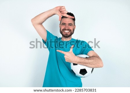 young handsome man wearing blue T-shirt over white background making finger frame with hands. Creativity and photography concept.