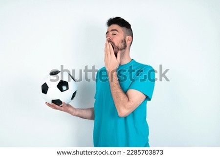 young handsome man wearing blue T-shirt over white background being tired and yawning after spending all day at work. Royalty-Free Stock Photo #2285703873