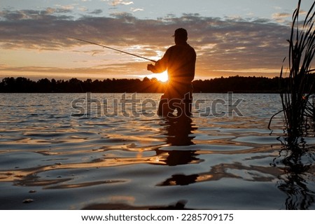 Fisherman wearing a chest wader standing in the lake fishing at sunset with lens flare defect.
 Royalty-Free Stock Photo #2285709175