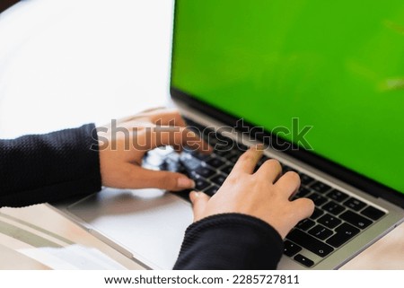 Woman's hands typing on laptop with green screen, horizontal photo, right side view
