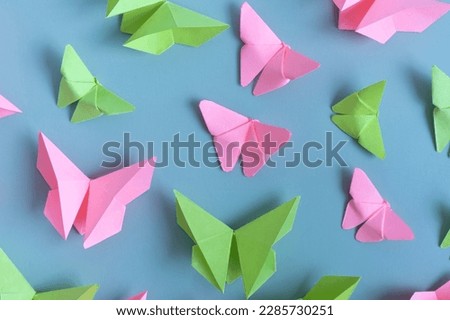 Paper butterfies green and pink color flat lay on a colored background. Lightness, spring beauty concept.