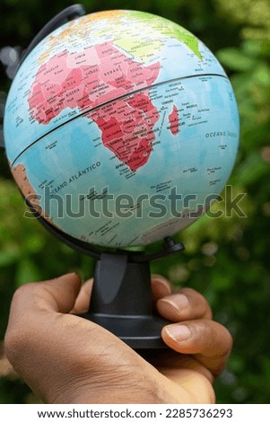 hand holding a terrestrial globe showing  Africa continent with green background