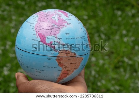 hand holding a terrestrial globe with green background  showing North and South America