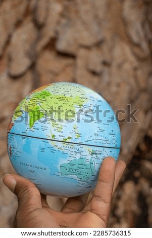 hand holding a terrestrial globe with texture background showing Asia and Oceania