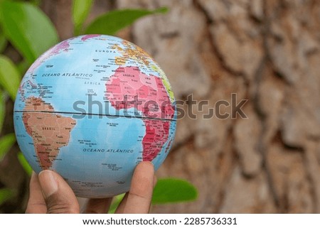 hand holding a terrestrial globe with wooden texture background   showing Sout America and an Africa