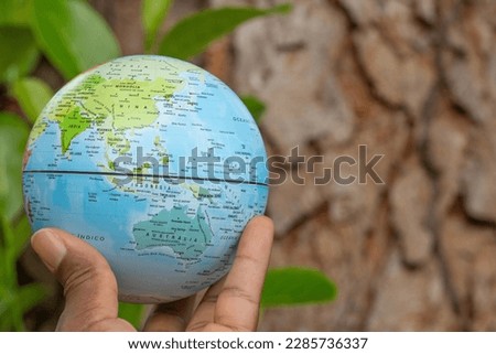 hand holding a terrestrial globe with wooden texture background  Asia and Oceania