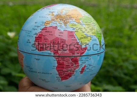 hand holding a terrestrial globe with green background