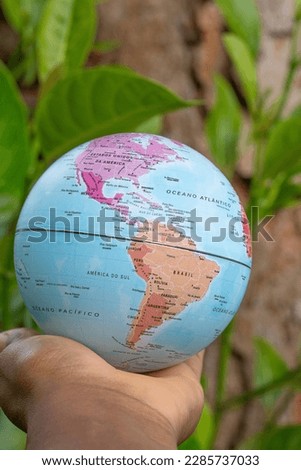 hand holding a terrestrial globe with wooden texture background  showing North and South America