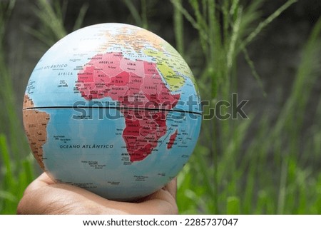 hand holding a terrestrial globe with green background  showing Africa