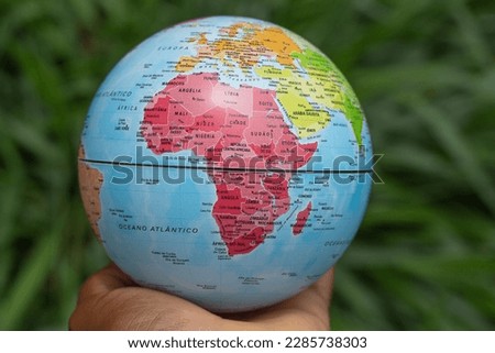 hand holding a terrestrial globe with green background