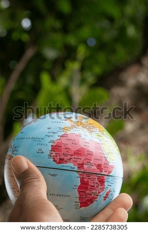 hand holding a terrestrial globe with green texture background  showing Africa continent