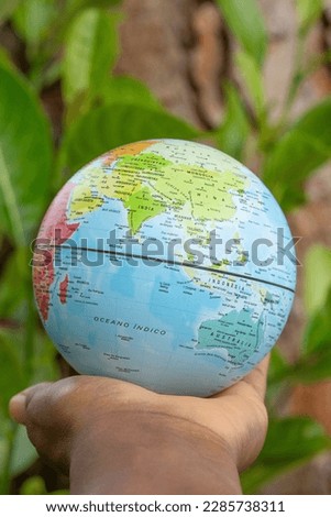 hand holding a terrestrial globe with wooden texture background  showing Asia and Australia