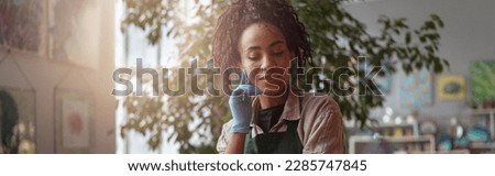 Woman florist takes care of seedlings in floral studio. Gardening concept. Blurred background