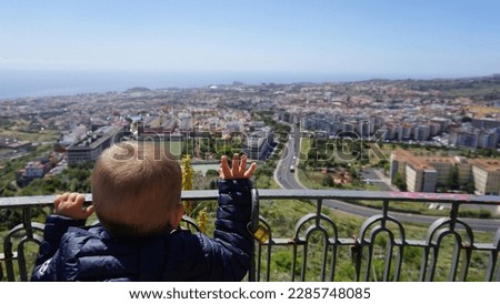 A little blonde boy looking at La Laguna town from San Roque viewing point, view from behind, Tenerife, Canary Islands, Spain 