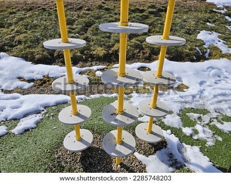 A closeup of playground equipment along a playground on a winter day.