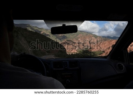 Journey. View from inside the car, of a man driving along the road across the rocky mountains. 