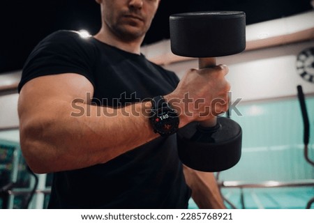 all screen graphics are made up. Professional female bodybuilder training muscles. Arms workout. Training biceps. fitness bracelet or smart watch on arm of sporty girl. inscription burning calories Royalty-Free Stock Photo #2285768921