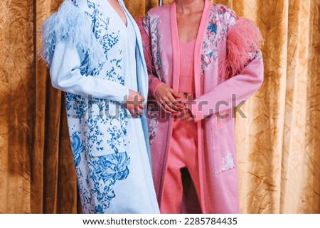 Two cropped female figures in pink blue stylish elegant clothes cardigans on backstage Fashion week