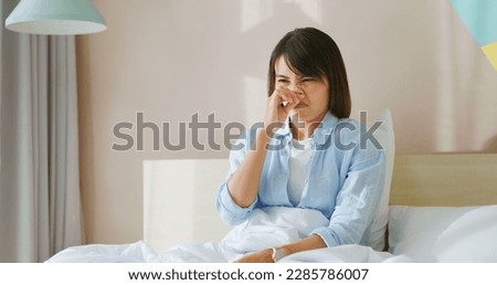 asian woman has allergy and she feel uncomfortable about her itchy running nose on bed in bedroom Royalty-Free Stock Photo #2285786007